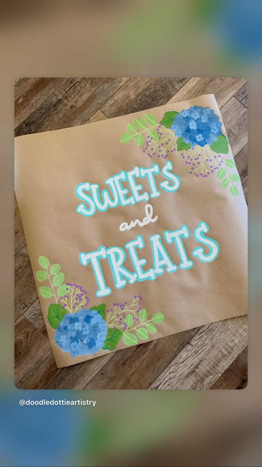 A 'Sweets and Treats' dessert-table sign hand-painted with blue hydrangeas.